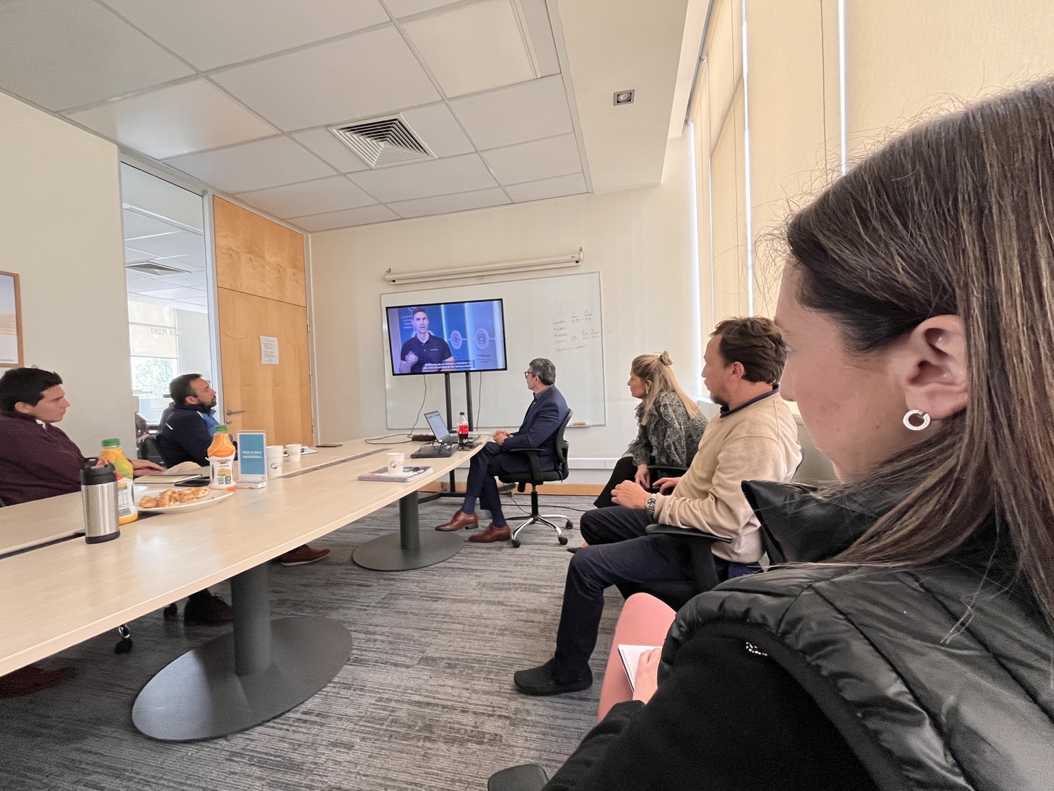 Personas reunidas alrededor de una mesa mirando una presentación